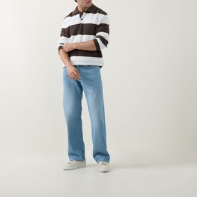 Model wearing Diesel 3049 loose jeans in light blue denim, styled with a brown striped polo shirt and white trainers.