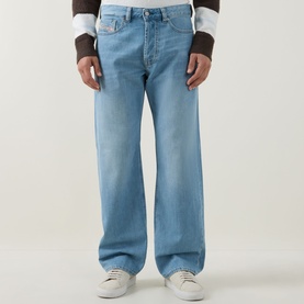 Model wearing Diesel 3049 loose jeans in light blue denim, styled with white trainers and a layered long-sleeve top.