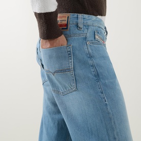 Model wearing Diesel 3049 loose jeans in light blue denim, styled with a dark brown knit top, close-up of hip and pocket detail.