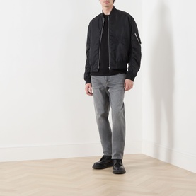 Model wearing Diesel 1993 D-VYL Slim Leg Jeans in grey with black bomber jacket and black leather shoes.