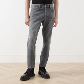 Model wearing Diesel 1993 D-VYL Slim Leg Jeans in grey with faded whiskering detail, styled with black leather boots and a black top.