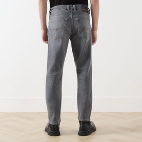Model wearing Diesel 1993 D-VYL Slim Leg Jeans in grey, rear view, styled with black loafers and a black top.