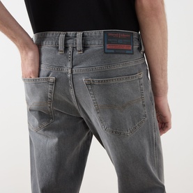 Model wearing Diesel 1993 D-VYL Slim Leg Jeans in grey, showing rear five-pocket detail and logo badge on waistband.