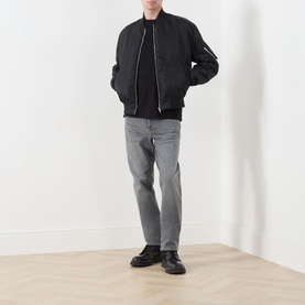 Model wearing Diesel 1993 D-VYL Slim Leg Jeans in grey, styled with a black bomber jacket and black boots.