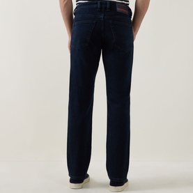 Model wearing Diesel 3049 slim jeans in dark blue denim, rear view, styled with a white stripe top and white trainers.