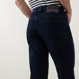 Model wearing Diesel 3049 slim jeans in dark blue denim, rear view, with white striped top. Red branded label at waistband.