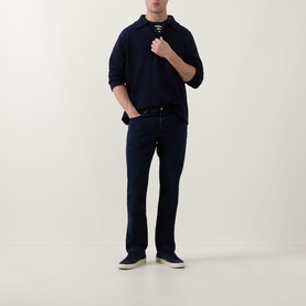 Model wearing Diesel 3049 slim jeans in dark blue, styled with a navy knit polo and navy canvas shoes.