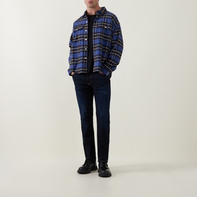 Model wearing Diesel 3049 slim jeans in dark blue, styled with a blue plaid overshirt and black boots