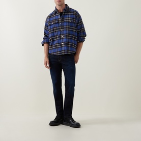 Model wearing Diesel 3049 Slim Jeans in dark blue, styled with a blue plaid overshirt and black boots.