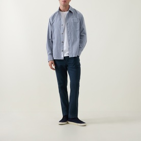 Model wearing Diesel 1993 D-VYL Slim-Leg Jeans in dark blue wash, styled with a light blue overshirt and white tee.