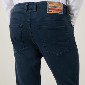 Model wearing Diesel 1993 D-VYL Slim-Leg Jeans in blue, showing rear five-pocket detail, logo patch, and tonal stitching