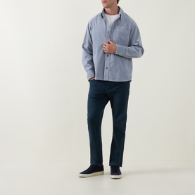 Model wearing Diesel 1993 D-VYL Slim-Leg Jeans in blue dark wash, styled with a chambray overshirt, white tee and navy slip-on shoes.