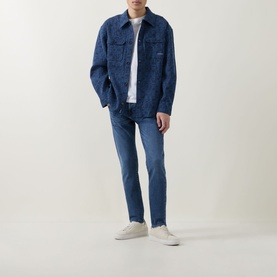 Model wearing Diesel 3049 slim jeans in mid blue, styled with a denim overshirt, white tee and cream trainers.