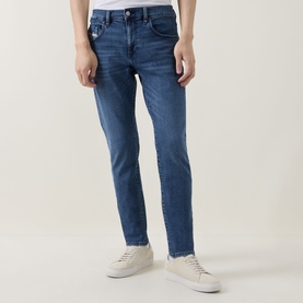 Model wearing Diesel 3049 slim jeans in mid blue denim, styled with white low-top trainers