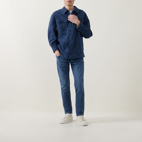 Model wearing Diesel 3049 Mid Blue slim jeans styled with a dark denim overshirt and white trainers.