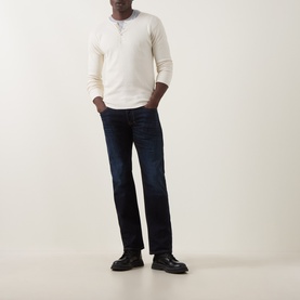 Model wearing Diesel 1985 Larkee Straight Leg Jeans in dark blue with whiskering details, styled with cream henley top and black leather shoes.