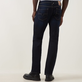 Model wearing Diesel 1985 Larkee Straight Leg Jeans in dark blue with tobacco stitching and logo badge, styled with black shoes.