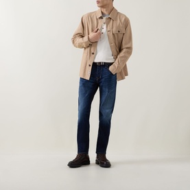 Model wearing Diesel 3049 dark blue tapered jeans, styled with a beige overshirt, white tee, and brown leather boots