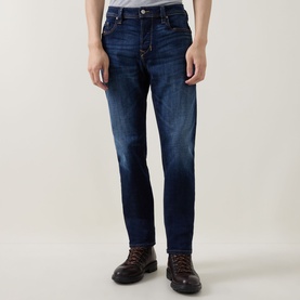 Model wearing Diesel 3049 dark blue tapered jeans with faded wash detail, styled with brown leather boots.