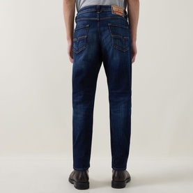 Model wearing Diesel 3049 dark blue tapered jeans, rear view, styled with black leather shoes