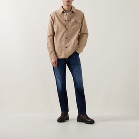 Model wearing Diesel 3049 dark blue tapered jeans, styled with a beige overshirt and brown lace-up boots.