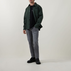 Model wearing Diesel 3049 tapered grey jeans, styled with a dark green overshirt and black shoes.