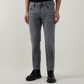 Model wearing Diesel 3049 grey tapered jeans, styled with black chunky-sole boots. Slim through thigh, tapered leg, five-pocket design.