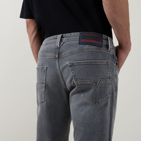Model wearing Diesel 3049 grey tapered jeans, back view showing rear pockets and branded belt loop detail, styled with black T-shirt.