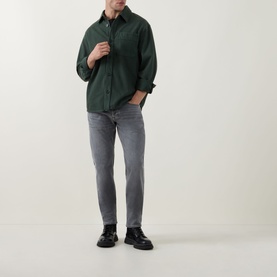 Model wearing Diesel Grey Tapered Jeans 3049, styled with a dark green shirt and black chunky loafers