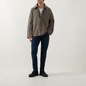 Model wearing Diesel 3049 Tapered Jeans in blue, styled with a khaki overshirt and black leather shoes.