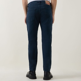 Model wearing Diesel 3049 blue tapered jeans, rear view, styled with black leather shoes. Cotton-elastane blend.