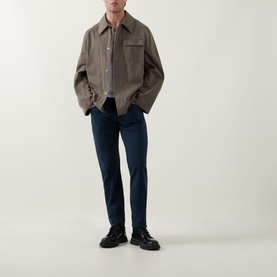 Model wearing Diesel 3049 tapered blue jeans, styled with a brown overshirt and black chunky loafers