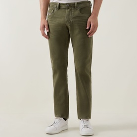 Model wearing Diesel 1986 Larke-Beex Tapered Jeans in green khaki wash, low-rise with tonal stitching, styled with white trainers.