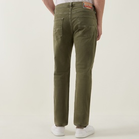 Model wearing Diesel 1986 Larke-Beex Tapered Jeans in green khaki wash, rear view showing logo patch and tonal stitching, styled with white trainers.