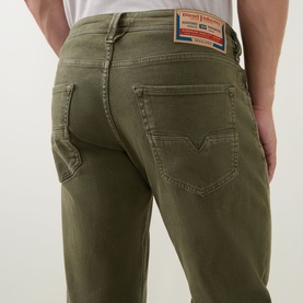 Model wearing Diesel 1986 Larke-Beex Tapered Jeans in green, showing rear five-pocket detail, logo patch, and tonal stitching.
