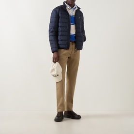Model wearing Gant Evening Blue quilted down casual jacket, styled with striped knit, tan chinos, dark loafers, and cream cap.