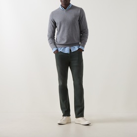 Model wearing Gant Classic Shield Sweater in dark grey melange, crew neck with ribbed trims, styled with a light blue shirt and dark trousers.