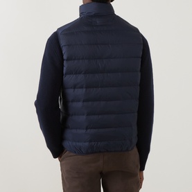 Model wearing Gant Evening Blue quilted down gilet, styled with navy knit jumper and brown trousers, rear view.
