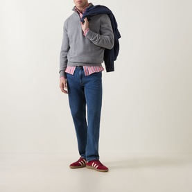 Model wearing Gant Shield Logo Half-Zip Sweatshirt in dark grey melange, styled with pink stripe shirt, blue jeans and red trainers.