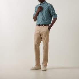 Model wearing Gant Dark Emerald striped regular fit cotton shirt, styled with beige chinos, tan belt and cream trainers.