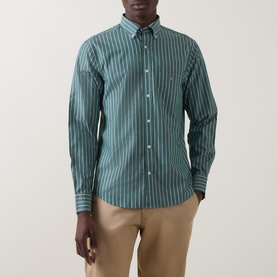 Model wearing Gant Reg Shirt in dark emerald vertical stripe cotton, styled with beige chinos. Button-down collar, chest pocket.