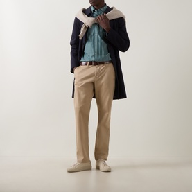 Model wearing Gant Dark Emerald Reg Shirt with navy overcoat, tan chinos, brown belt, and cream trainers.