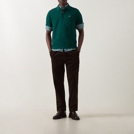Model wearing Gant Dark Emerald Regular Polo in cotton, styled with a check shirt, brown trousers and leather loafers.