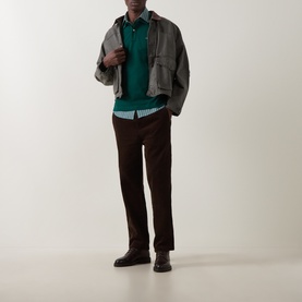 Model wearing Gant Regular Polo in dark emerald, styled with grey jacket, light shirt, dark brown trousers and black leather shoes.