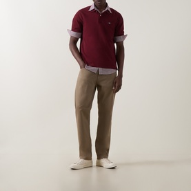 Model wearing Gant Regular Polo in Deep Grape Wine, styled with khaki chinos and white trainers.