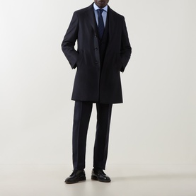 Model wearing Canali navy wool coat, styled with matching navy trousers, light blue shirt and tie, and black loafers.