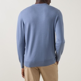 Model wearing Canali Fine-Knit Sweater in light blue, crew neck, long sleeves, fine wool knit, shown from the back with beige trousers.