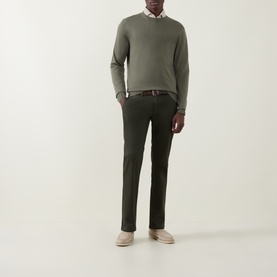 Model wearing Canali Fine-Knit Sweater in green crew neck, styled with dark chinos, a shirt, belt, and beige suede shoes.
