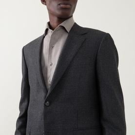 Model wearing Canali Prince Of Wales Check Suit Jacket in charcoal, single-breasted with notch lapel, styled with a taupe shirt.