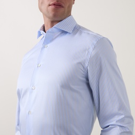 Model wearing Canali light blue fine stripe cotton formal shirt with spread collar and single button cuff detail.